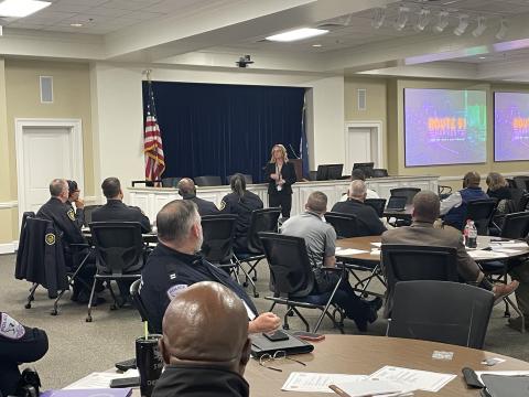 A group of people sitting and listening to a speaker at the front of the room.