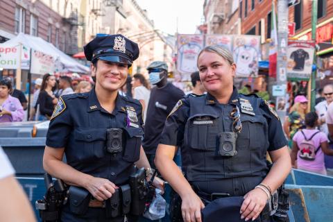 Two law enforcement officers smiling, standing in front of a community event.